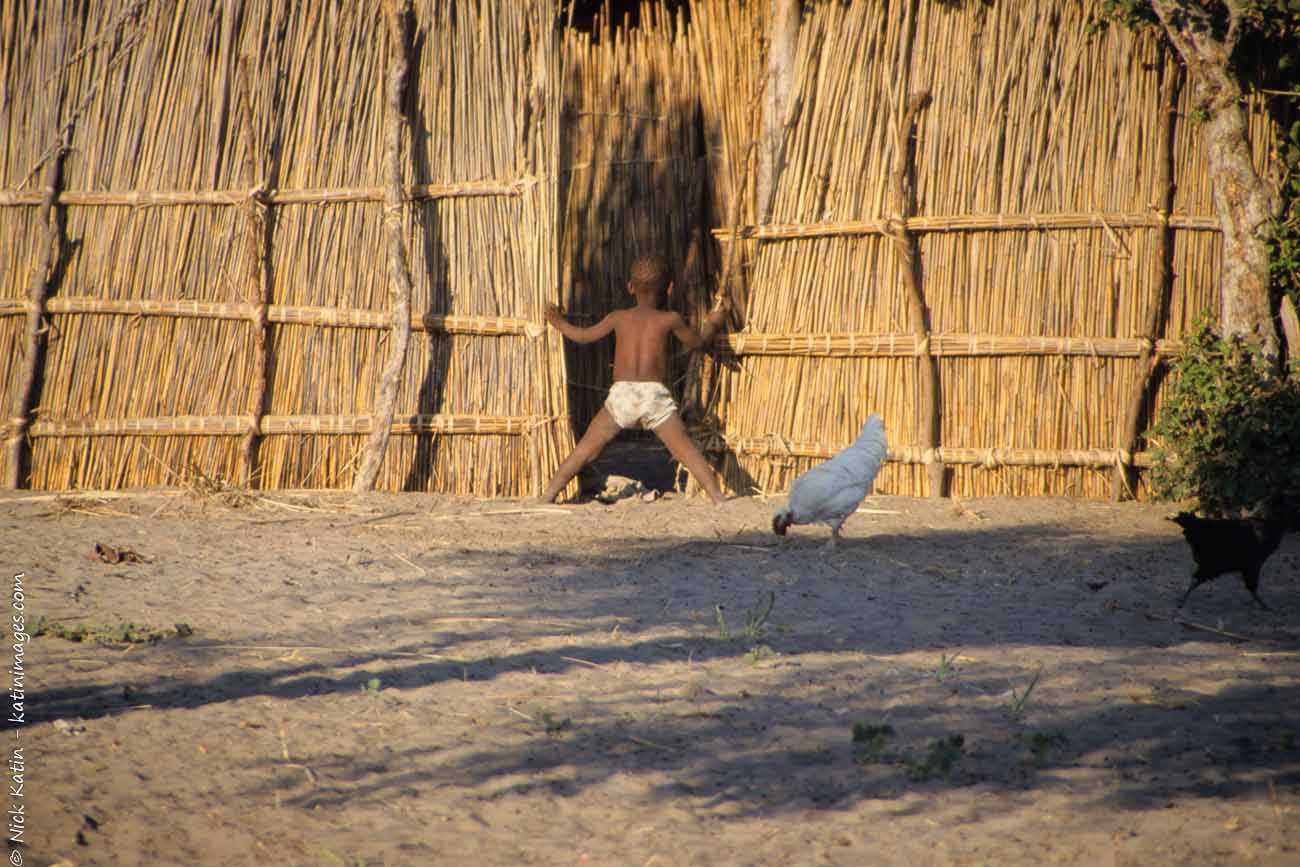 Young boy peeking in a hut in a small village in Botswana