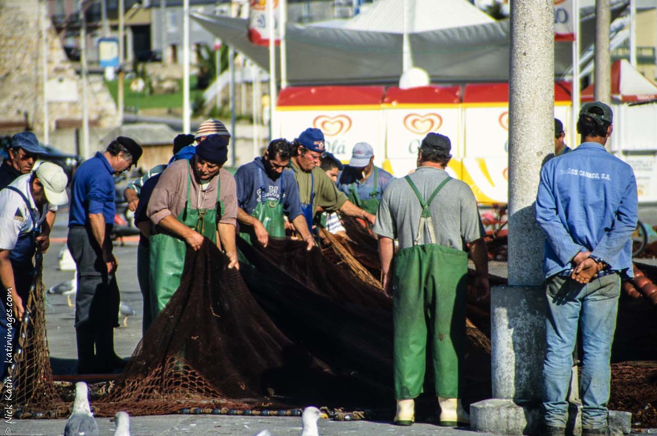 Fishereman organising their nets on the jetty in Peniche, Portugal